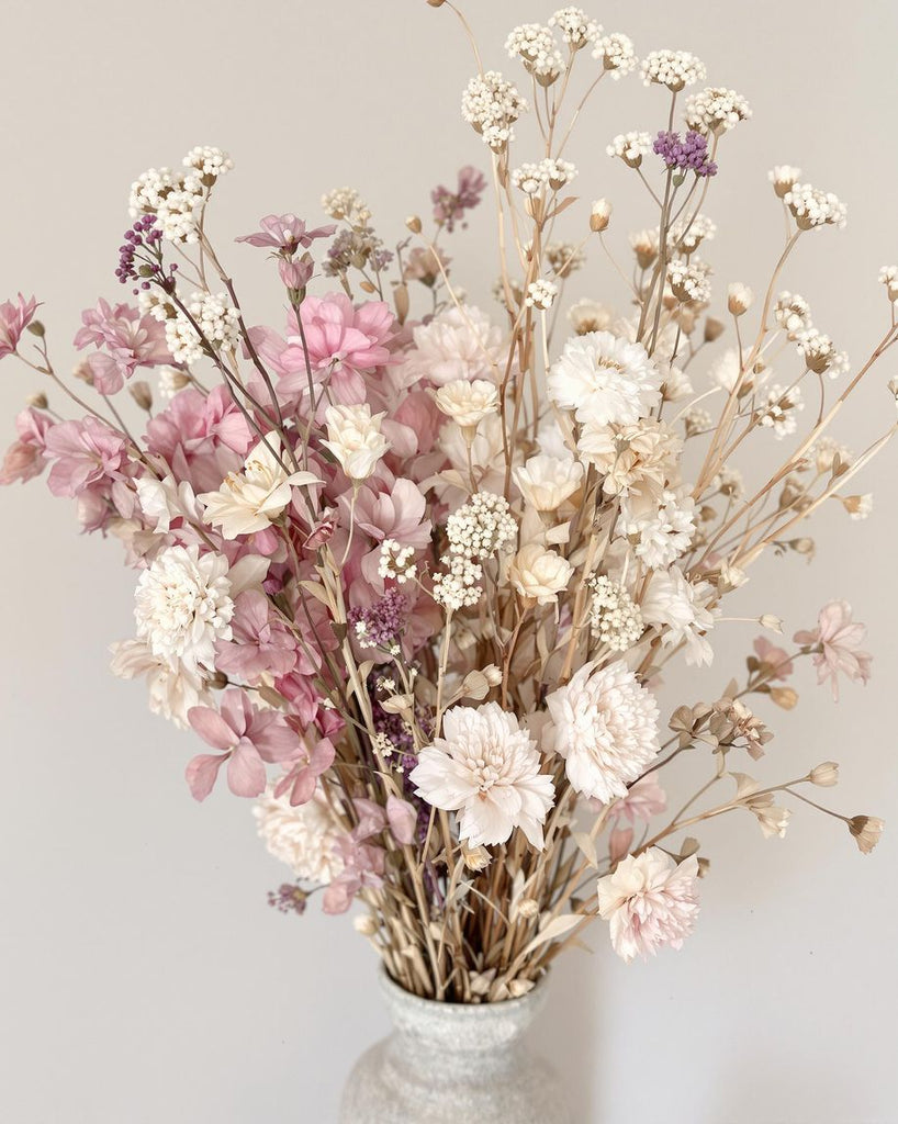 Dried flower arrangements in soft pastel colours in a vase.